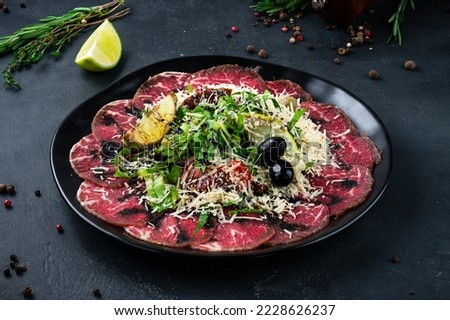 Veal carpaccio salad with vegetable and parmesan cheese. Restaurant menu, dieting. Beef carpaccio: beef tenderloin, romaine lettuce, sun-dried tomatoes, parmesan cheese.
