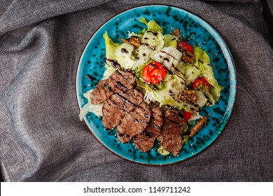 Veal Salad With Lettuce, Apple, Pear And Tomato On Blue Plate On Dark Wooden Background, Copy Space. Restaurant Food, Close Up. Meat Salad