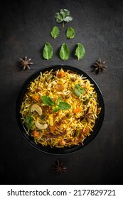 Veg Biryani Tabletop Photography Styled On Black-grey Texture Background Garnished In Black A Bowl With Fresh Ingredients Like Mints Leaves, Lemon, And Star Anise. Copy Space Is For The Matter.