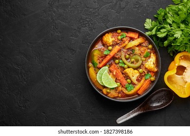 Veg Kolhapuri in black bowl on dark slate table top. Indian vegetable curry dish. Vegetarian asian food and meal. Copy space. Top view