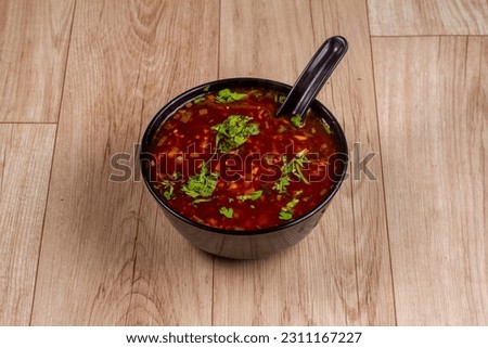 Veg Manchow Soup in black bowl on wooden background