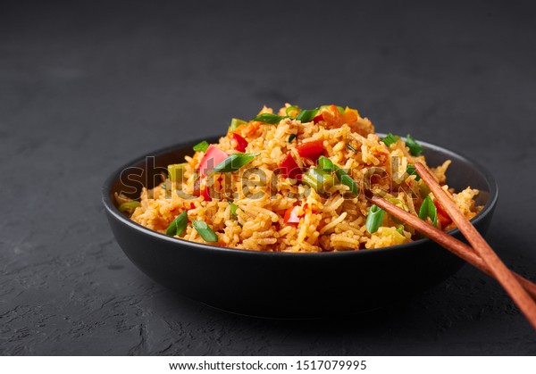 Veg Schezwan\
Fried Rice in black bowl at dark slate background. Vegetarian\
Szechuan Rice is indo-chinese cuisine dish with bell peppers, green\
beans, carrot. Copy space