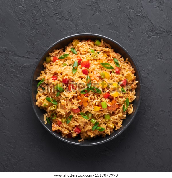 Veg Schezwan Fried\
Rice in black bowl at dark slate background. Vegetarian Szechuan\
Rice is indo-chinese cuisine dish with bell peppers, green beans,\
carrot. Top view