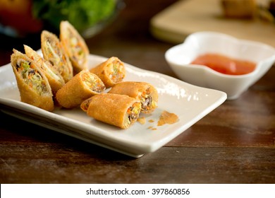 Veg. Spring Rolls, on white dish and wooden table / Selective focus