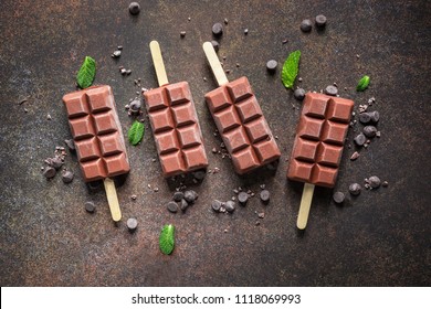 Vegan Banana Chocolate Fudge Popsicles  Decorated With Mint Leaves, Chocolate Chips. Creamy Dairy Free Ice Pop. Dark Background