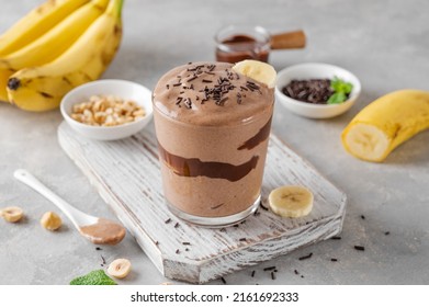 Vegan banana chocolate ice cream with chocolate glaze and sprinkles in a glass on a gray concrete background. Healthy food. Copy space - Powered by Shutterstock