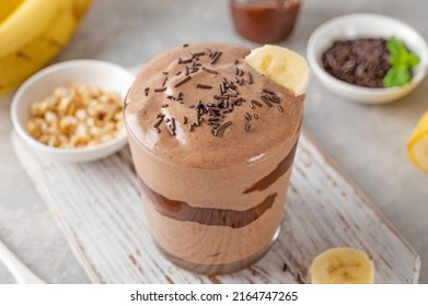 Vegan banana chocolate ice cream with chocolate glaze and sprinkles in a glass on a gray concrete background. Healthy food. Copy space - Powered by Shutterstock