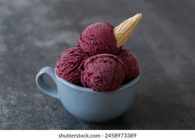 Vegan beetroot ice cream in a waffle cone in a mug on a concrete background. Healthy vegan frozen dessert. 
