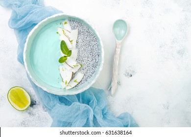 Vegan Blue Spirulina Smoothie And Chia Pudding Bowl Topped With Coconut Flakes And Lime Zest. Overhead, Flat Lay, Top View, Copy Space