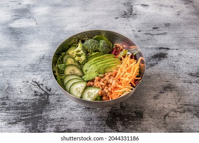 Vegan Bowl With Pieces Of Cucumber, Broccoli Sprigs, Grated Carrots And Beets, Arugula And Spinach, Stewed Lentils And Ripe Avocado