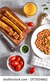 Vegan Breakfast With Homemade  Lentil Sausages, Beans, Orange Jouice And Tomatoes Laying On The Grey Table