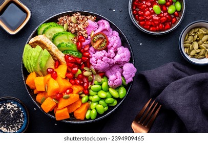 Vegan buddha bowl with baked pumpkin, quinoa, avocado, edamame soybeans, fried tofu, cauliflower, pomegranate and seeds, black table background, top view. Autumn or winter healthy vegetarian food - Shutterstock ID 2394909465