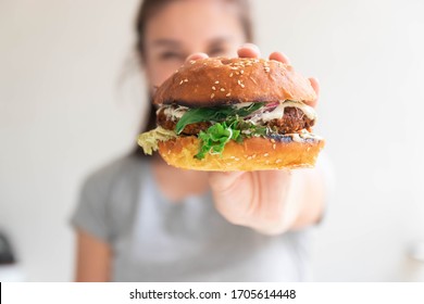 Vegan burger closeup in girl hands. Happy woman tasting and biting burger - Powered by Shutterstock