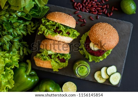 Vegan burgers with beet cutlet and green smoothies on black background. Healthy vegan food. Detox diet. Flat lay.