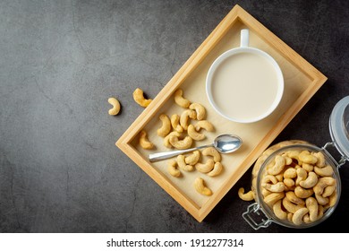 Vegan cashew milk in glass with cashews nuts on dark background