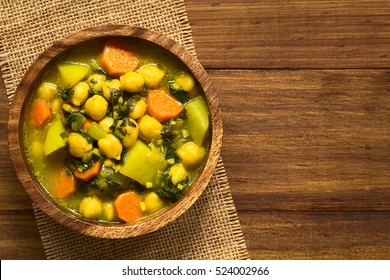 Vegan Chickpea Curry Or Chana Masala With Spinach, Potato And Carrot Served In Wooden Bowl, Photographed Overhead With Natural Light (Selective Focus, Focus On The Top Of The Curry)