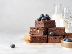 Vegan Chocolate Brownie With Nuts And Blueberry. Brownie Chewy Squares Stack With Fresh Berries And Cocoa Powder On Baking Paper. Morning Table. Copy Space. White Background.