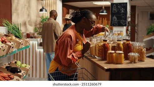 Vegan client examining types of pasta on sale at zero waste store, supporting local small business and low carbon footprint movement. Woman searching for natural eco friendly food supplies. Camera 2. - Powered by Shutterstock