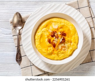 vegan corn grits with butter, vegan cheese, and almonds in white bowl on white wood table with ingredients, horizontal view from above, flat lay, close-up - Shutterstock ID 2256901261