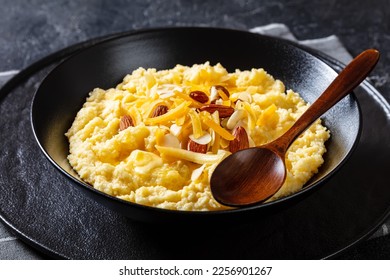 vegan corn grits with butter, vegan cheese, and almonds in black bowl on concrete table with spoon, landscape view from above, close-up - Shutterstock ID 2256901267