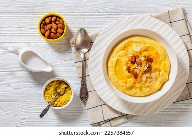 vegan corn grits with butter, vegan cheese, and almonds in white bowl on white wood table with ingredients, horizontal view from above, flat lay - Shutterstock ID 2257384557