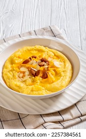 vegan corn grits with butter, vegan cheese, and almonds in white bowl on white wood table, vertical view - Shutterstock ID 2257384561