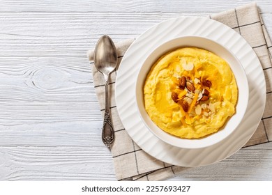 vegan corn grits with butter, vegan cheese, and almonds in white bowl on white wood table with ingredients, horizontal view from above, flat lay, copy space - Shutterstock ID 2257693427
