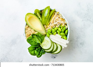 Vegan, detox green Buddha bowl recipe with quinoa, avocado, cucumber, spinach, tomatoes, mung bean sprouts, edamame beans, daikon radish. Top view, flat lay