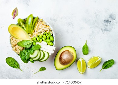 Vegan, detox green Buddha bowl recipe with quinoa, avocado, cucumber, spinach, tomatoes, mung bean sprouts, edamame beans, daikon radish. Top view, flat lay, copy space