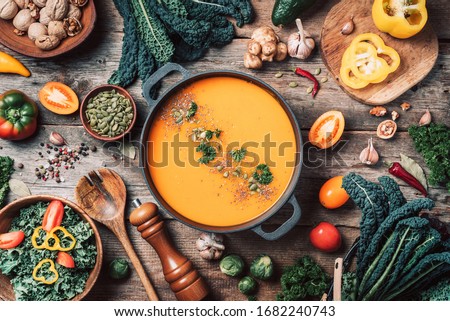 Vegan diet. Autumn harvest. Healthy, clean food and eating concept. Zero waste. Pumpkin soup with vegetarian cooking ingredients, wooden spoons, kitchen utensils on wooden background. Top view