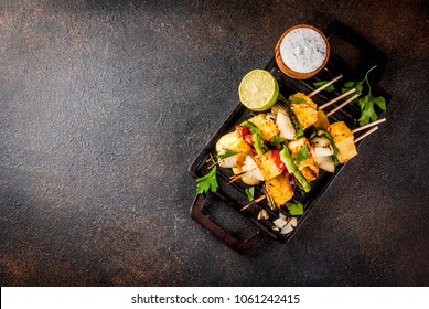 Vegan diet food, Grilled cheese and vegetables kebab, indian style Paneer Tikka, with white sauce and lime, on dark concrete background, copy space top view