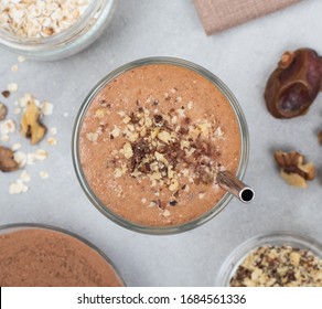 Vegan drink smoothies made from dried fruits, nuts, chocolate in a glass on a light gray background top view