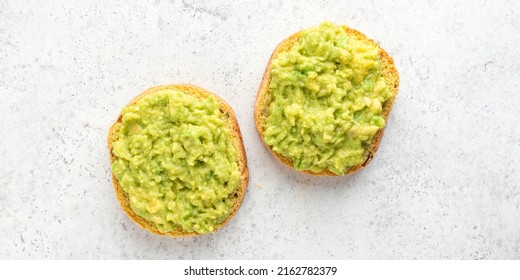 Vegan English Muffin Toast With Mashed Avocado On Grey Concrete Background, Top View. Banner