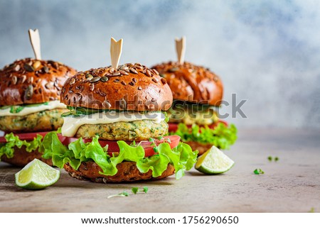 Vegan falafel burger with vegetables and sauce, dark background. Healthy food concept.