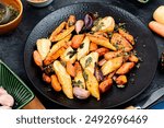 Vegan food of baked parsnip root and carrots. Roasted root vegetables.