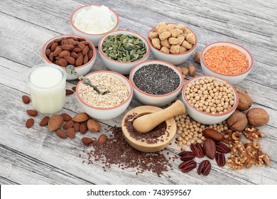 Vegan health food with soy beans, seeds, nuts, soya milk, yoghurt and chunks. Foods high in fiber, antioxidants, vitamins and minerals.  On rustic wood background.