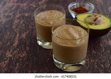 Vegan healthy banana avocado chocolate smoothie in glasses on wooden background