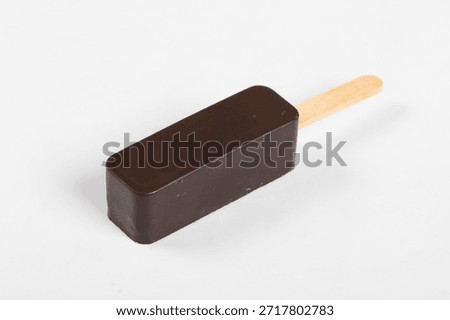 Vegan ice cream is rectangular in shape. In dark chocolate glaze. On a wooden stick. White background. Close-up.