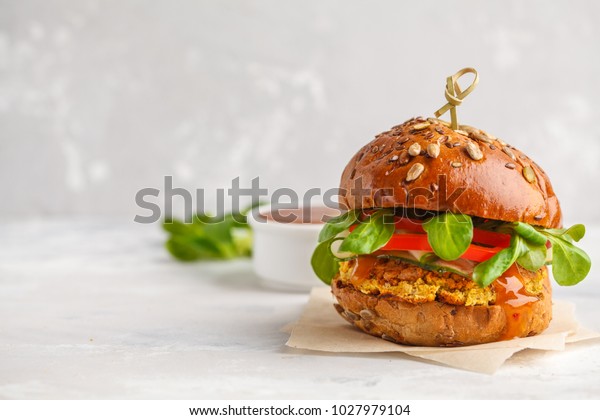 Vegan lentils burger with\
vegetables and curry sauce. Light background, copy space. Vegan\
food concept.