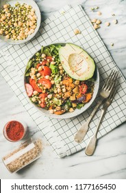 Vegan lunch bowl. Flat-lay of vegan dinner with avocado, mixed grains, beans, sprouts, greens and vegetables with salt and spices over marble table, top view. Vegetarian, healthy diet food concept