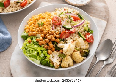 Vegan lunch bowl with roasted vegetables, fresh lettuce, cooked lentils, couscous salad and crunchy roasted chickpeas - Powered by Shutterstock