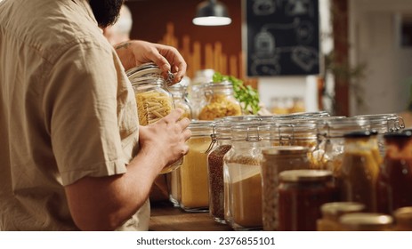 Vegan man in zero waste supermarket using decomposable paper bag while shopping for organic pantry staples. Customer in local neighborhood shop with no single use plastics policy, close up - Powered by Shutterstock