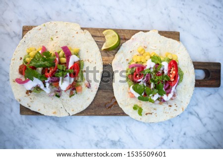 Vegan Mexican taco in wheat tortilla served on wooden platter in vegan restaurant