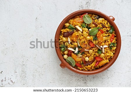 Vegan Moroccan Bulgur with Chick Peas, spinach, dried apricots and date fruit. Traditional African Tajine dish. Flat layot