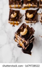 Vegan No-bake Chocolate Date And Coconut Healthy Bites With Peanutbutter And Syrup And Cashew Nut On Top Directly From Above On White Marble