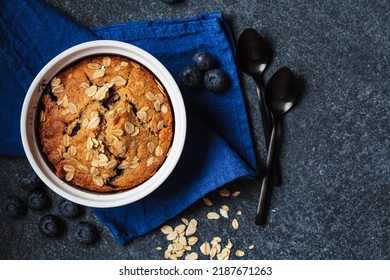 Vegan oatmeal, banana, blueberry mug muffin on blue background, top view. Plant based dessert. - Shutterstock ID 2187671263