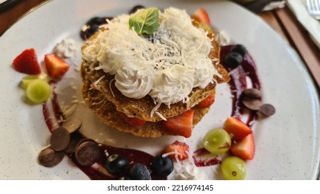 A Vegan Pancake Tower On A White Plate, Decorated With Fruits, Cream And A Fruitsauce