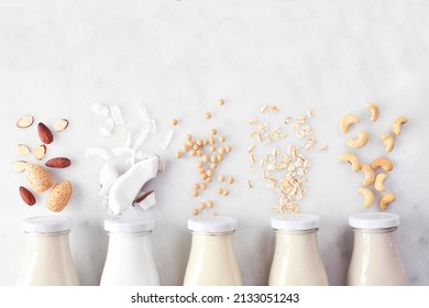 Vegan, plant based, non dairy milk. Variety in milk bottles with ingredients. Above view over a white marble background. - Shutterstock ID 2133051243