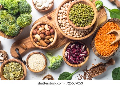 Vegan protein source. Beans, lentils, nuts, broccoli spinach and seeds. Top view on white table. Healthy vegetarian food. - Shutterstock ID 725609053