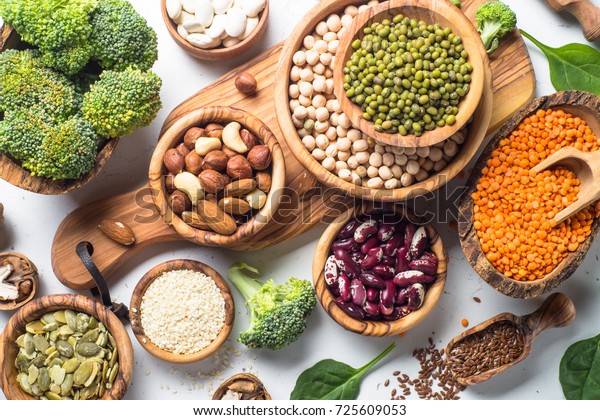 Vegan\
protein source. Beans, lentils, nuts, broccoli spinach and seeds.\
Top view on white table. Healthy vegetarian\
food.